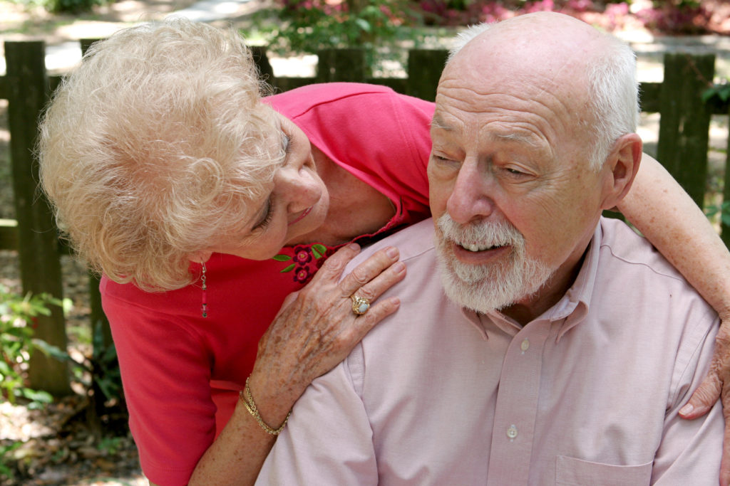 A senior couple. The wife is caring for the husband.