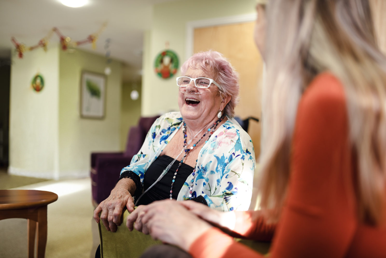 senior woman with dementia laughing with her daughter in home at Christmas