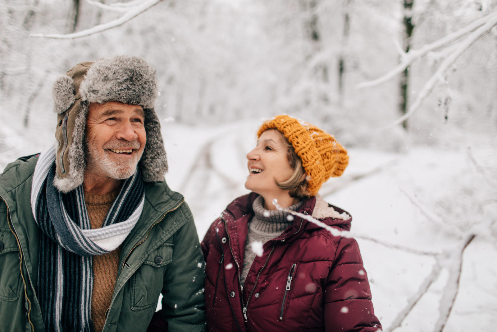 elderly couple who enjoy walking together on a cold snowy day while holding hands