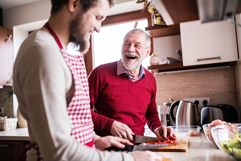 son cooking with smiling elder father