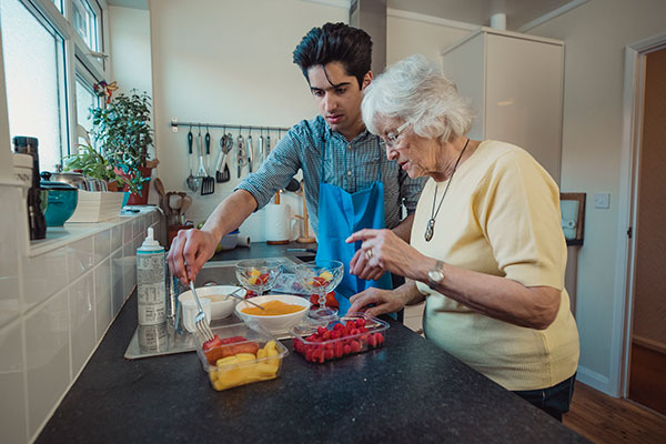 son helping elderly mother prepare dinner