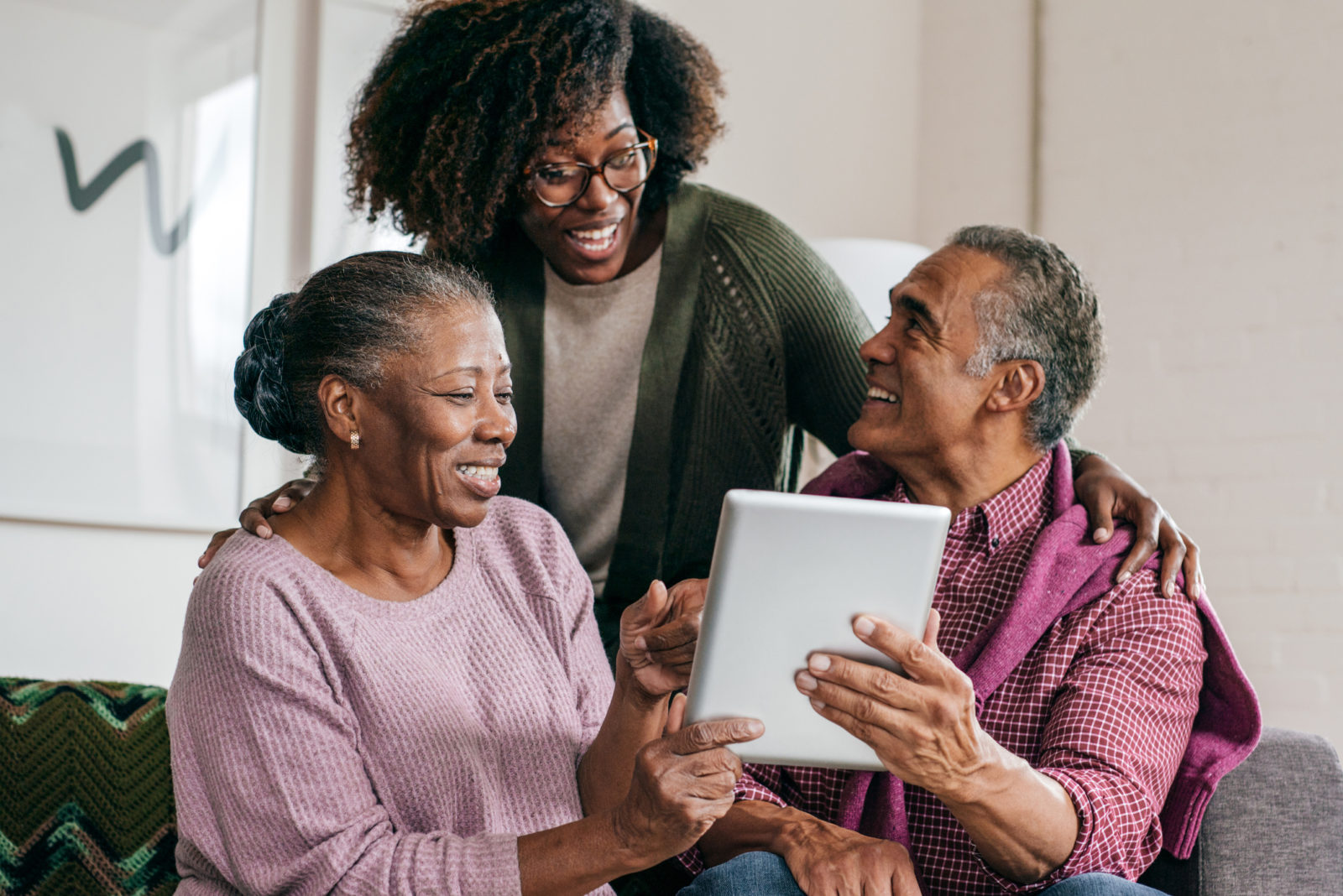 daughter with elder parents looking at computer tablet