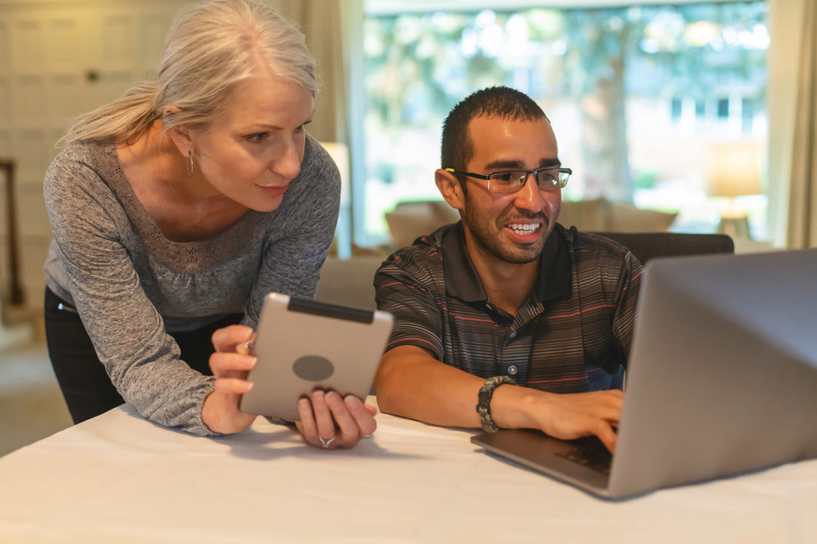 Mature Adult Female and Millennial Male Working Together on Technology in a Home Setting