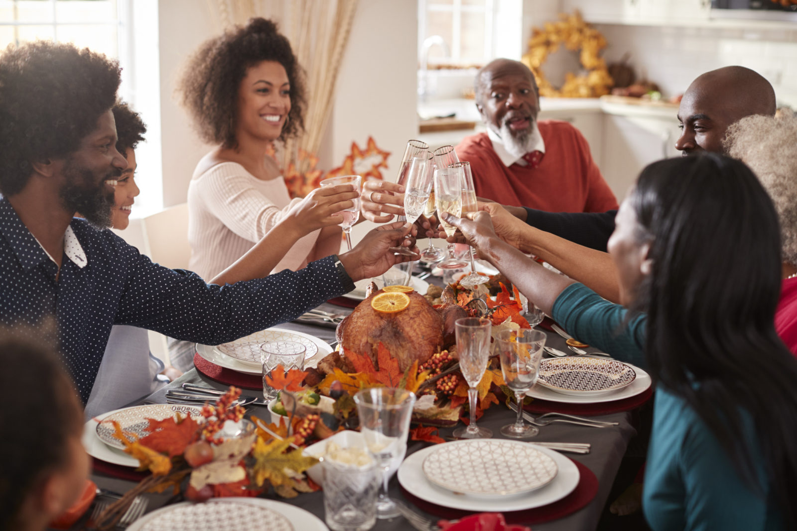 Multi generation mixed race family raise their glasses to make a toast at their Thanksgiving dinner table
