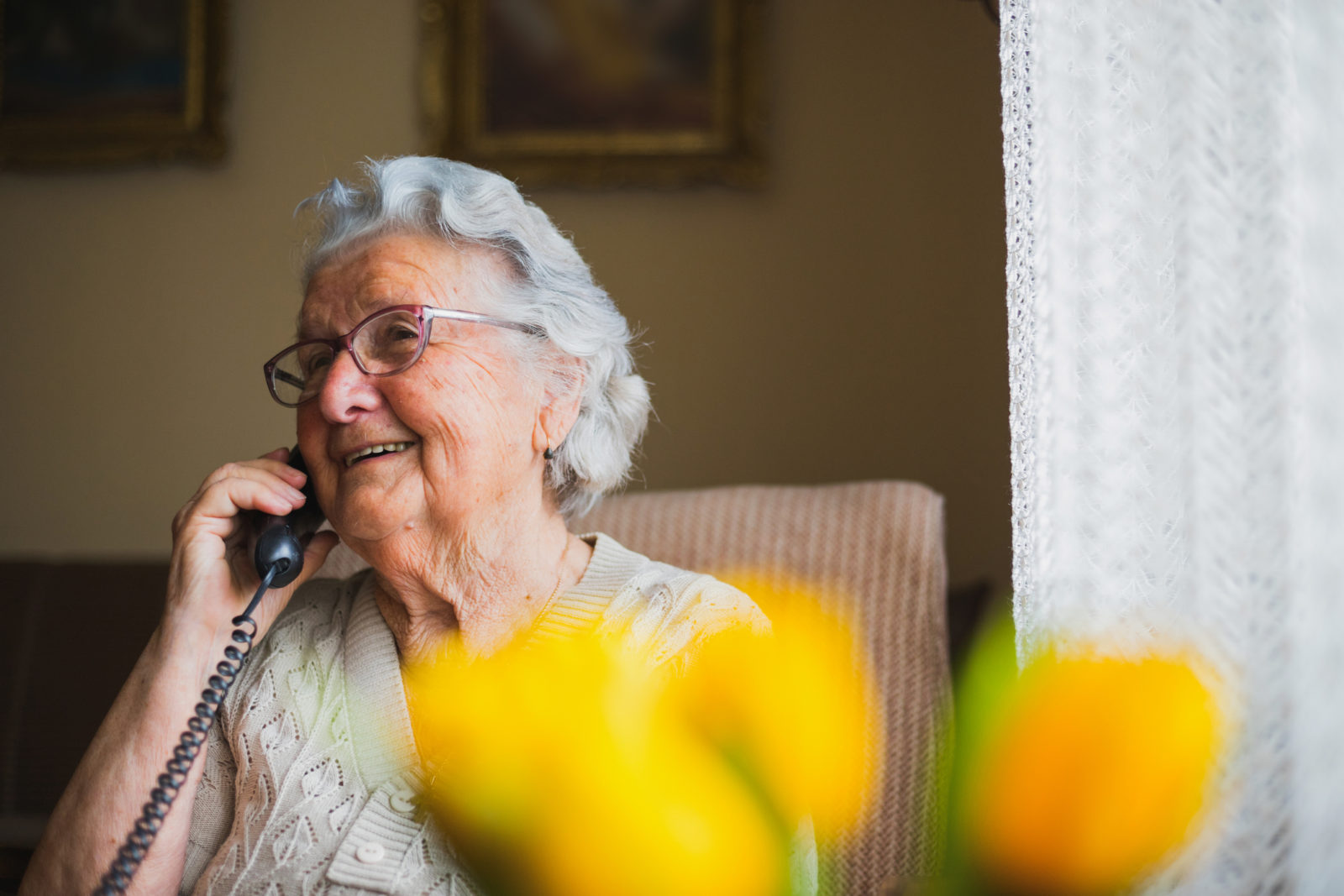 Senior white lady speaks to her daughter and son by telephone.