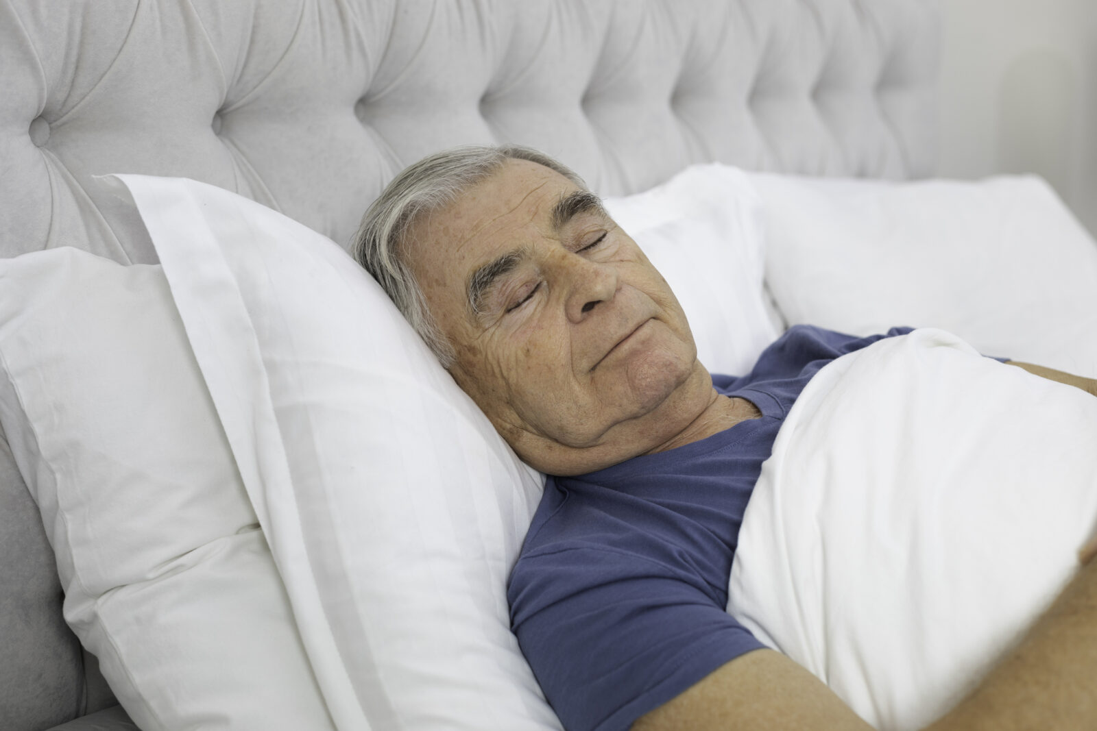 Senior man asleep in his bed.
