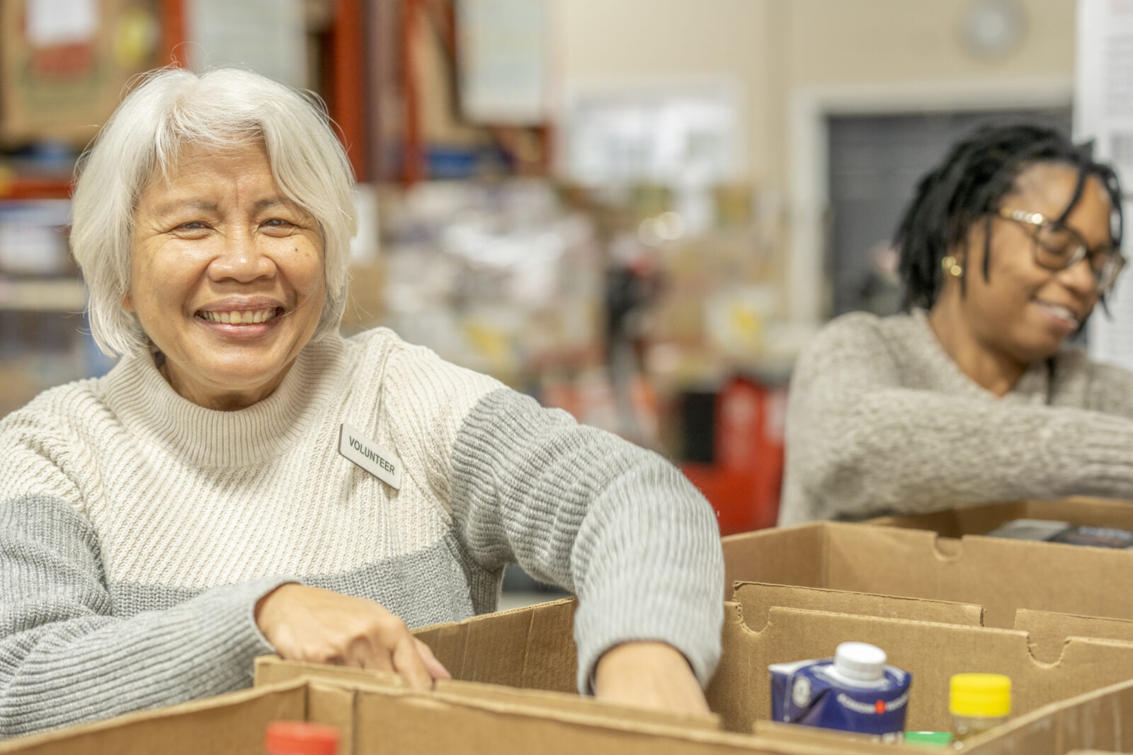 Two senior ladies work together as they volunteer their time at a local Food Bank.